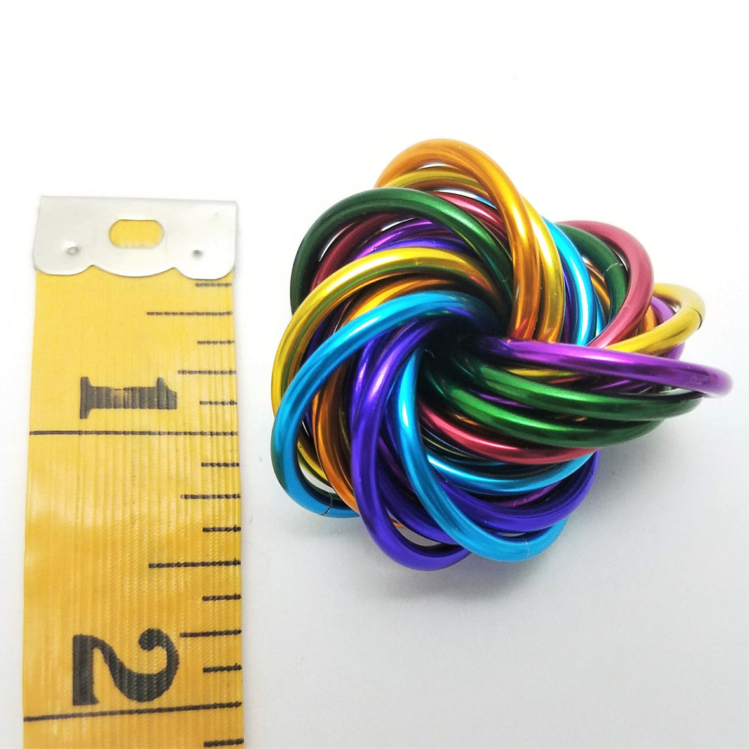 Shiny multicolor ring fidget stress ball next to a tape measure for size reference