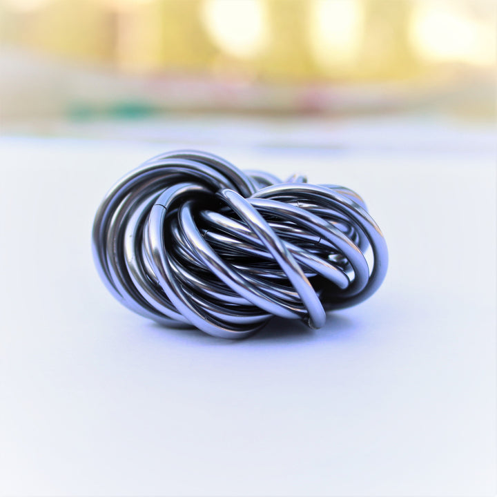 Swirled fidget stress ball, blue and silver glossy loops in a tight knot shape