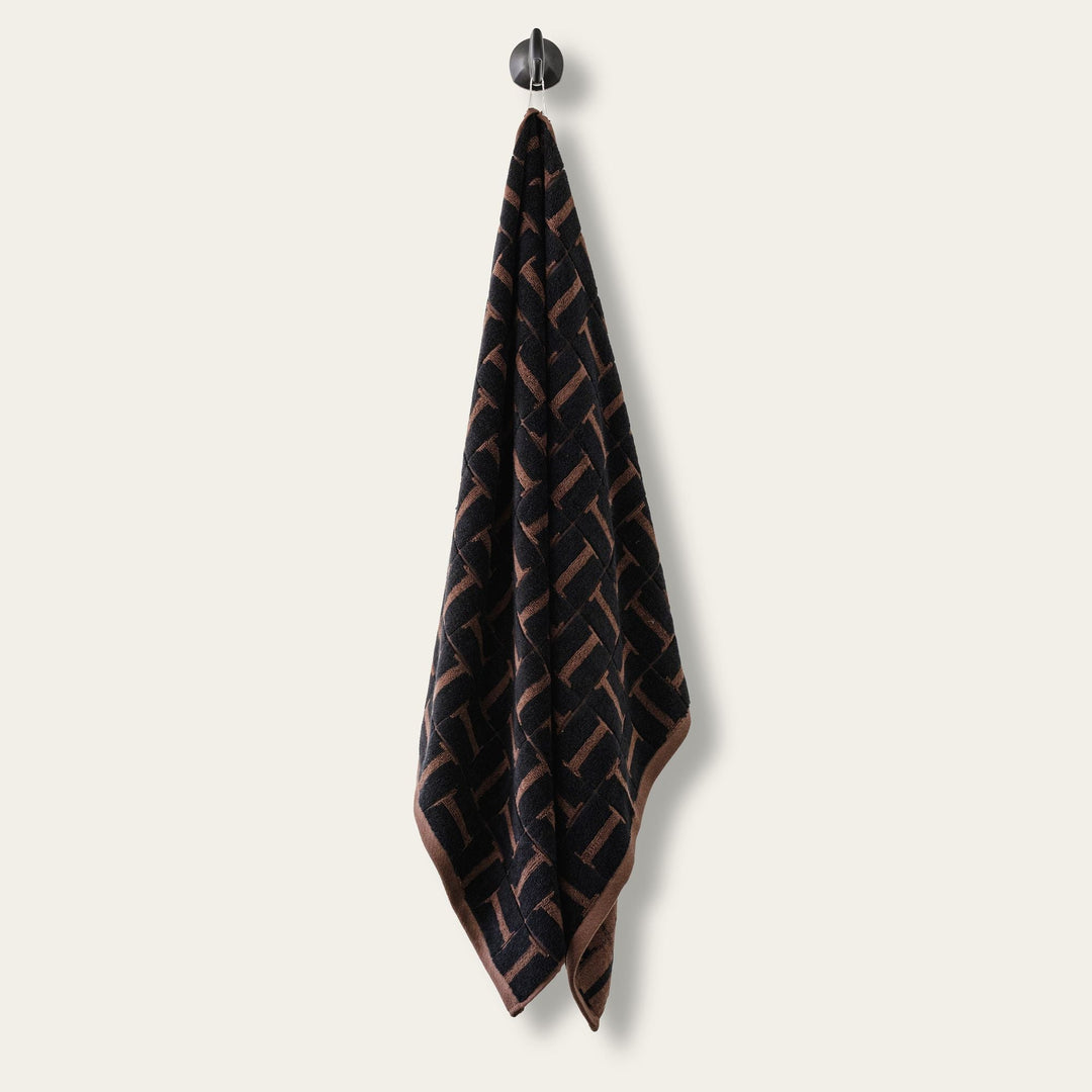 Hanging hand towel, dark base with tobacco-brown woven geometric pattern.