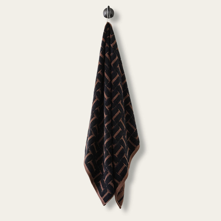 Hanging hand towel, dark base with tobacco-brown woven geometric pattern.