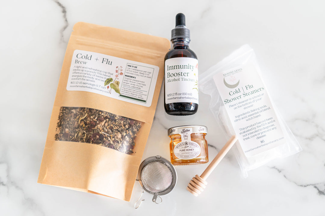Cold and flu wellness kit with tincture bottle, tea pouch, small jar, and strainer
