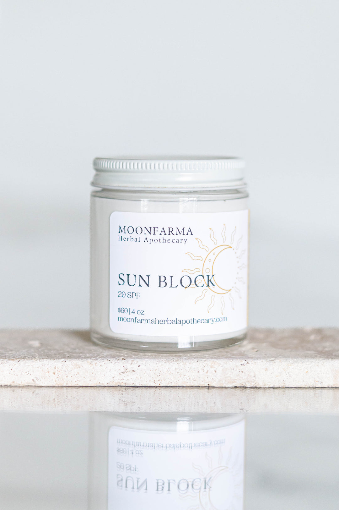 Sunscreen jar labeled SPF 20, clear plastic lid on stone tray