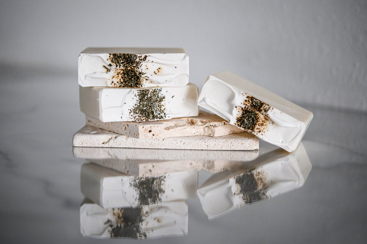 Stacked rectangular soap bars, white with green speckled centers and crumbly texture