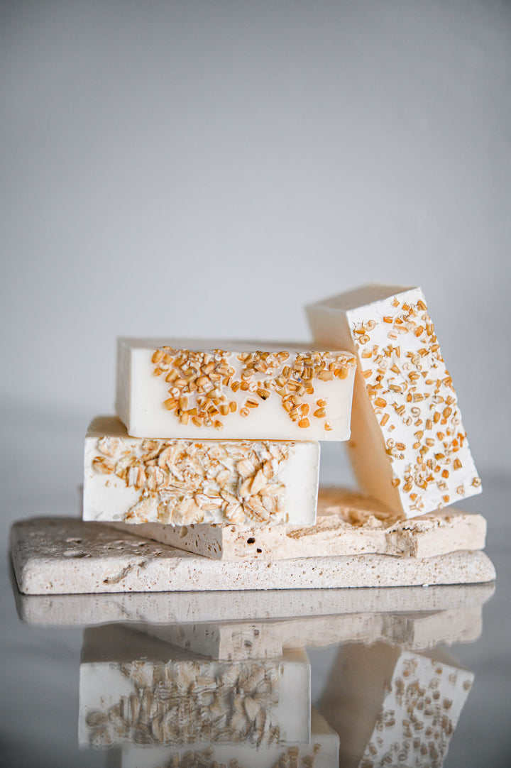 Oatmeal and honey handmade soap bars, off-white with orange speckles, three-bar stack, angled