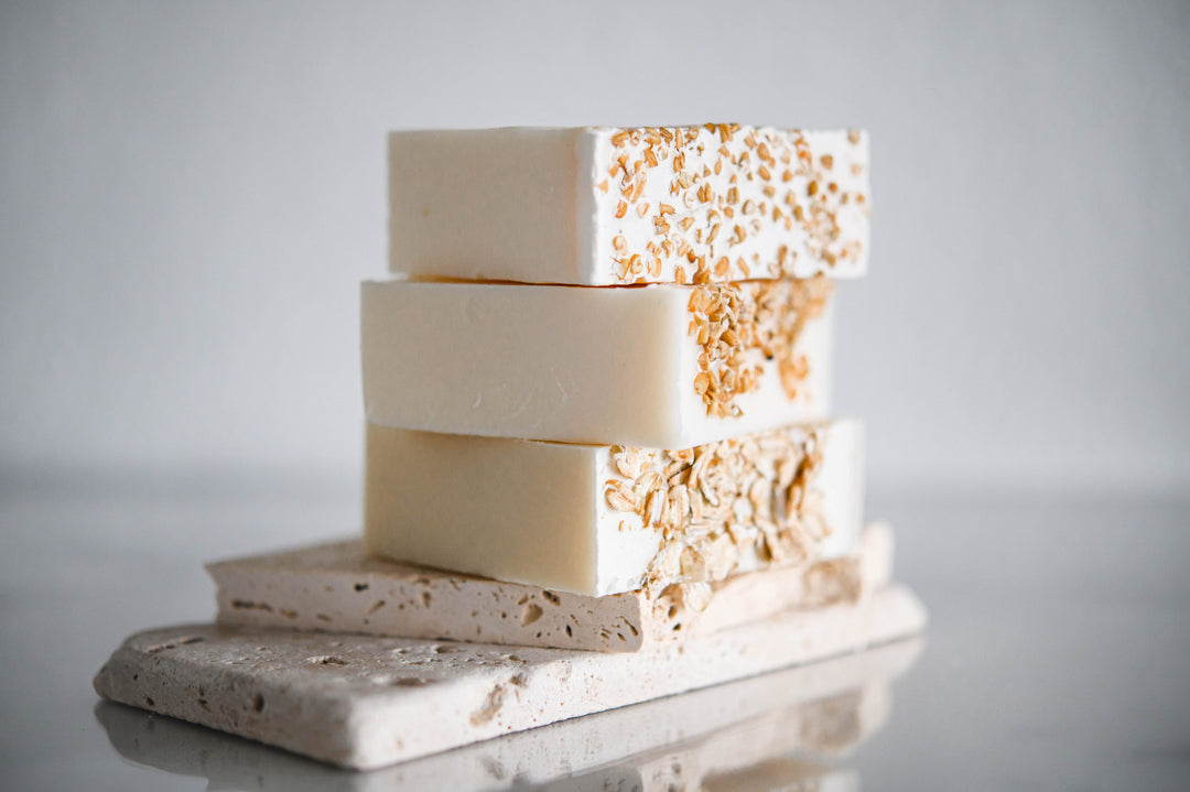 Oatmeal and honey handmade soap bars, off-white with orange speckles, close-up stack on gray