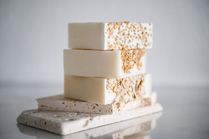 Oatmeal and honey handmade soap bars, off-white with orange speckles, close-up stack on gray