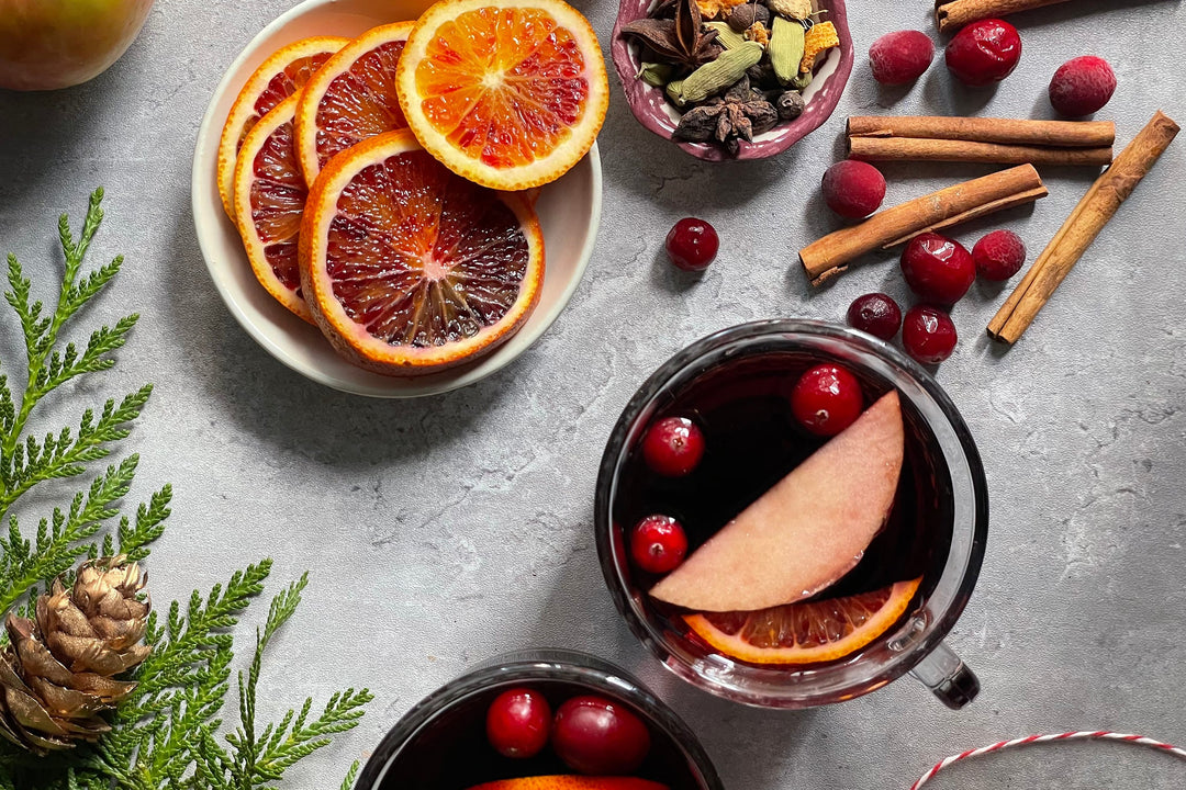 Mulled spice drink with orange slices and cranberries in a glass mug