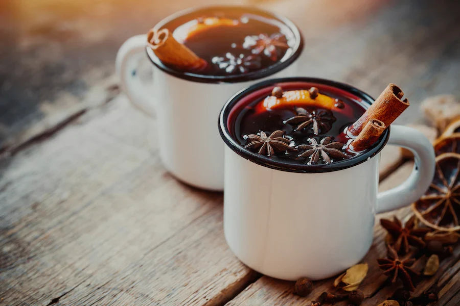 Two mugs of mulled spice tea with star anise and cinnamon sticks