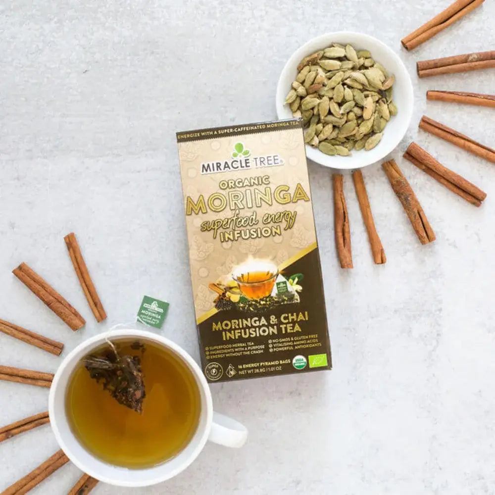 Organic moringa chai tea box with cup of tea and cinnamon sticks on table