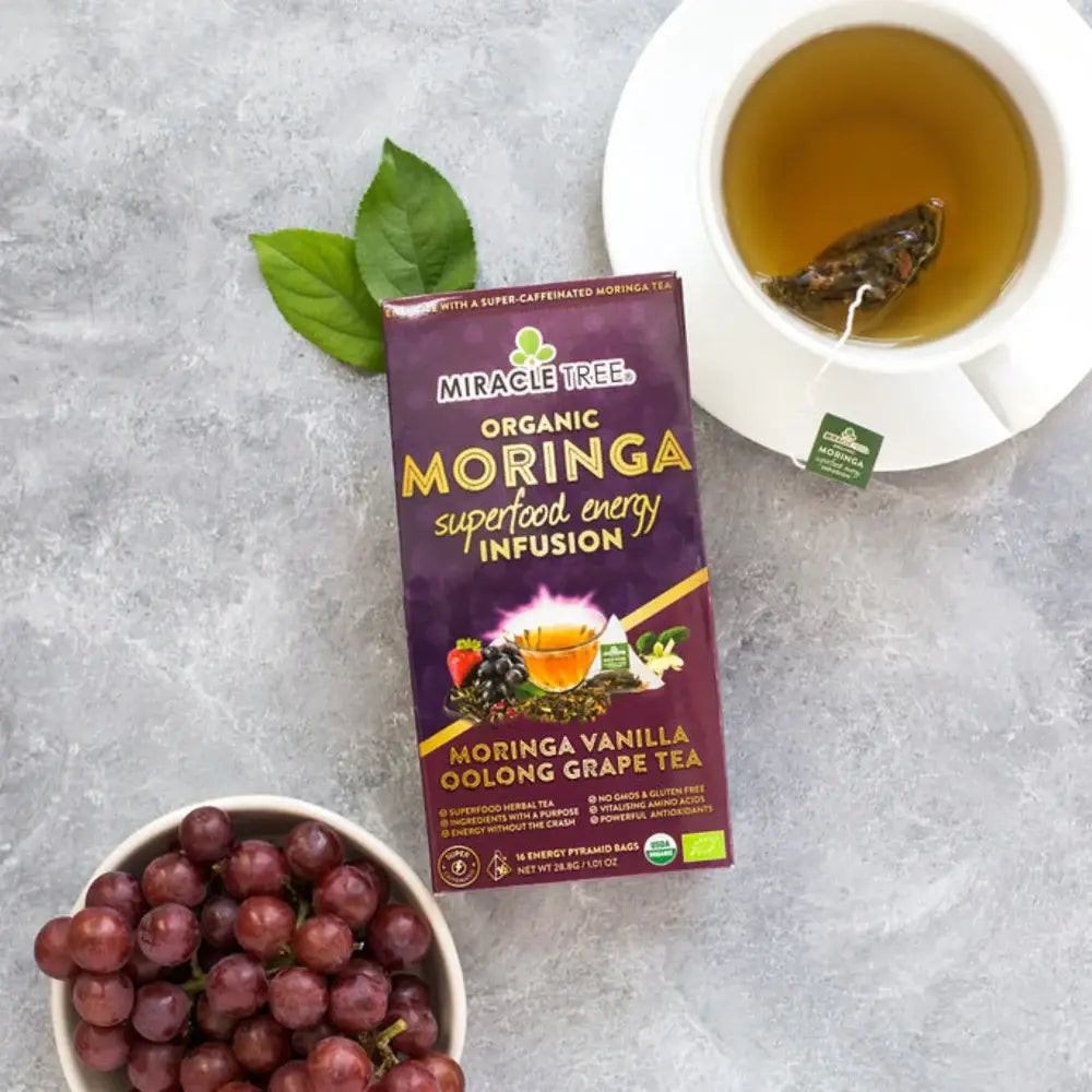 Organic moringa tea package with cup of hot tea and grapes and green leaf