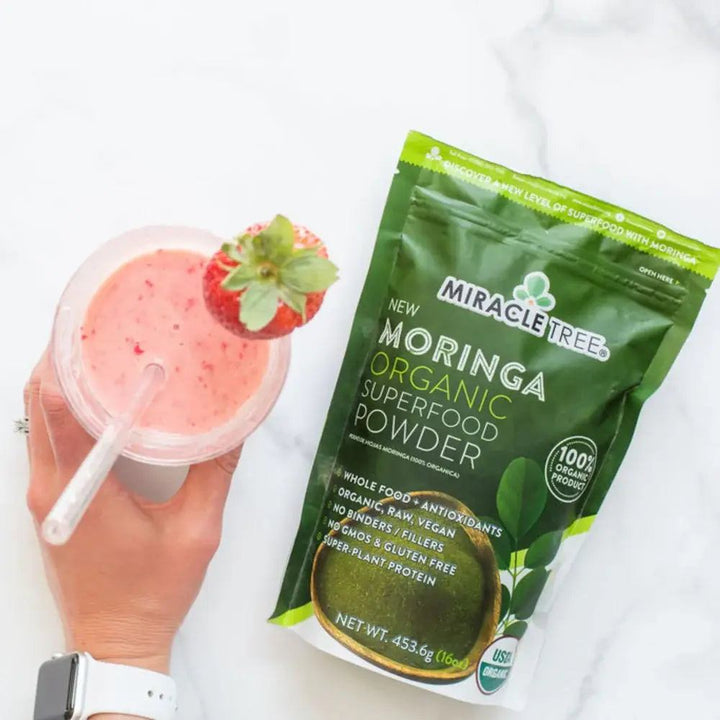 Miracle Tree organic moringa superfood powder pouch with smoothie cup nearby