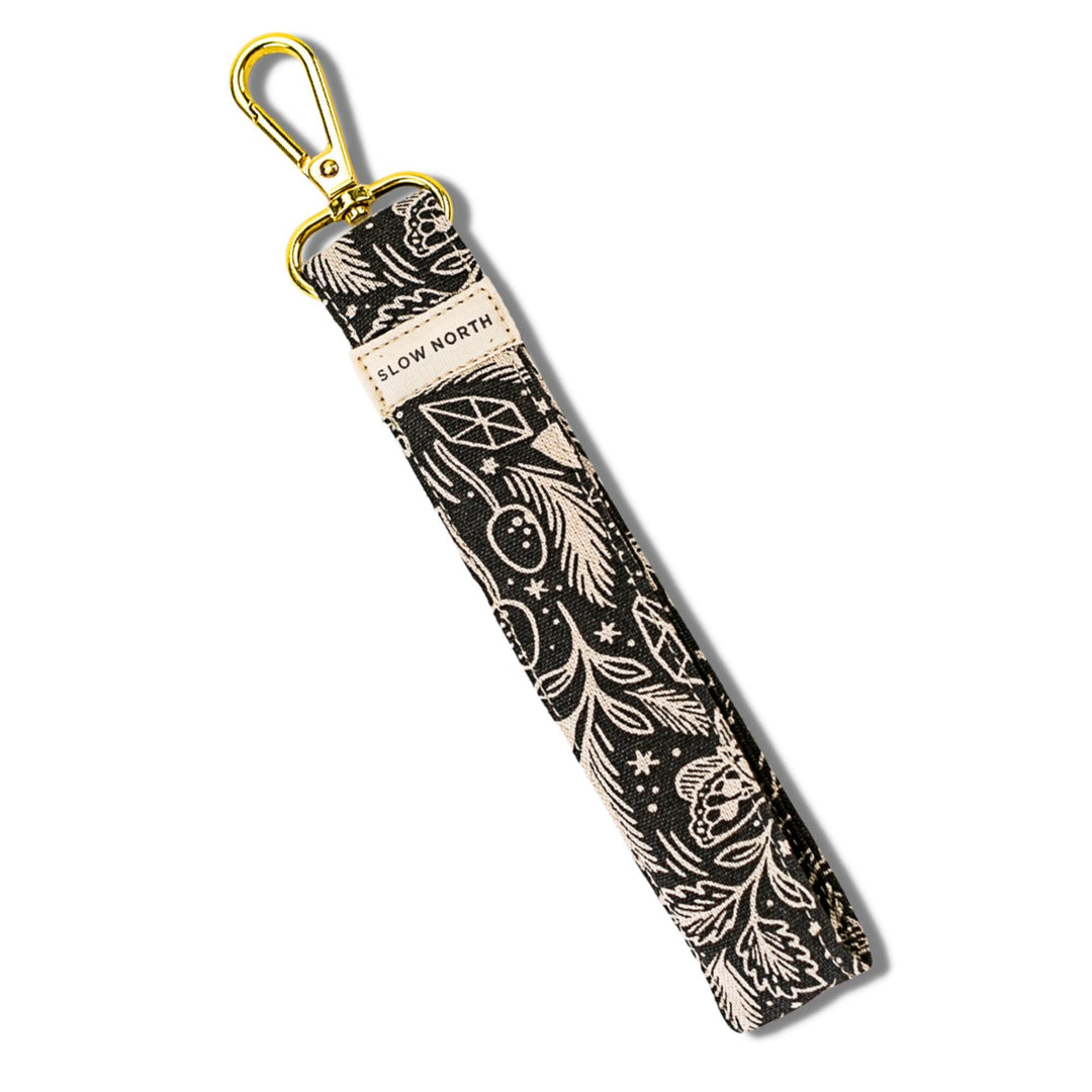 Black fabric wristlet keychain strap with white mystical mushroom print and gold key ring