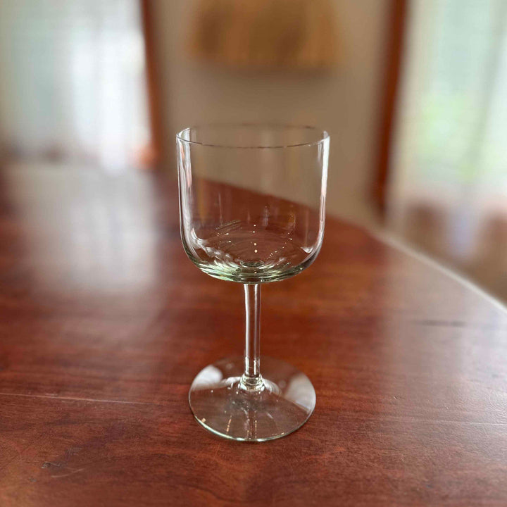 Stemmed wine glass filled with amber wine on wooden table