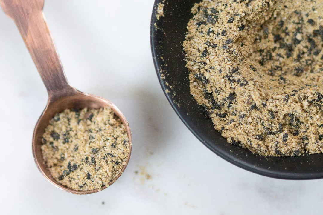 Ground spice blend in a metal scoop and large skillet