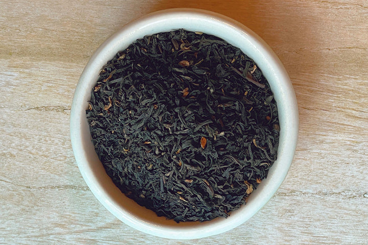 Loose dark tea leaves in a white bowl