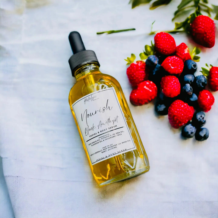 Amber Nourish serum bottle with black dropper near red and dark berries