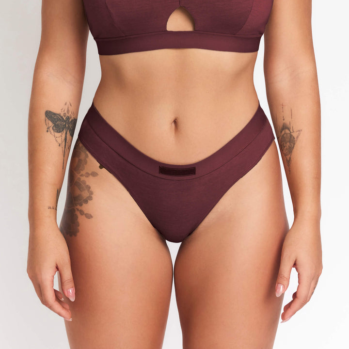 Burgundy mid-rise brief with wide waistband and smooth front leg openings.