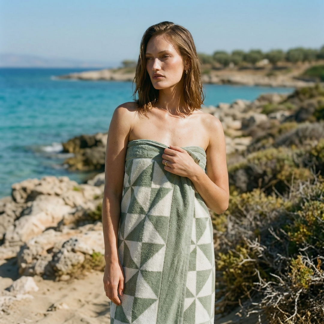 Green geometric cotton towel wrapped around a model outdoors by the sea.
