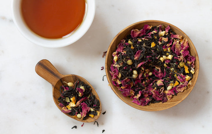 Rose herbal tea blend in wooden bowls with amber tea cup