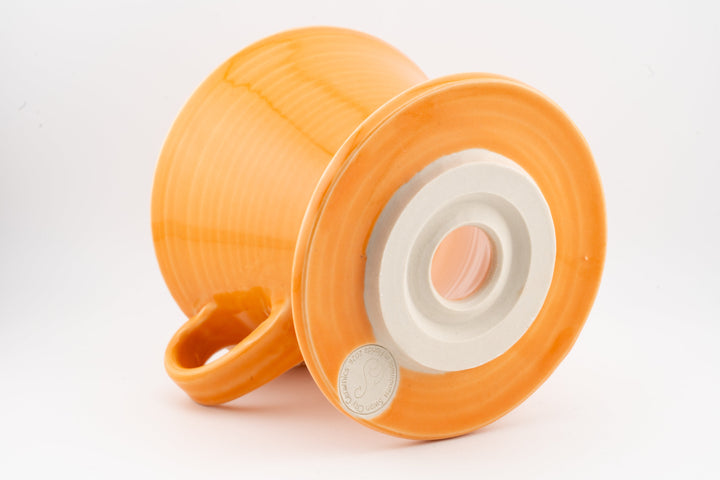 Orange ceramic pour-over dripper with inner filter ring and side handle, underside view