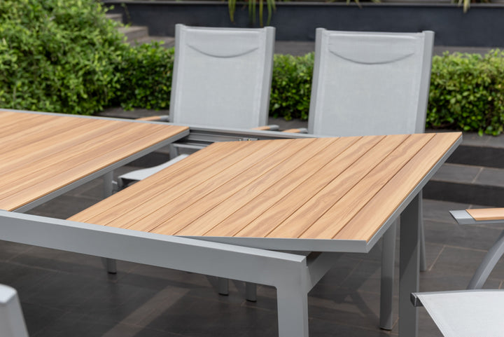 Extendable patio table with light wood slatted surface and gray metal base