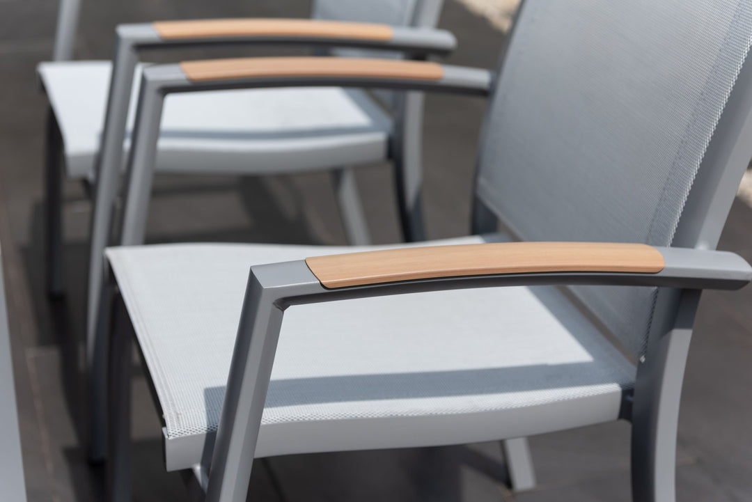 Close-up of gray outdoor dining chair armrests with white mesh seat panels