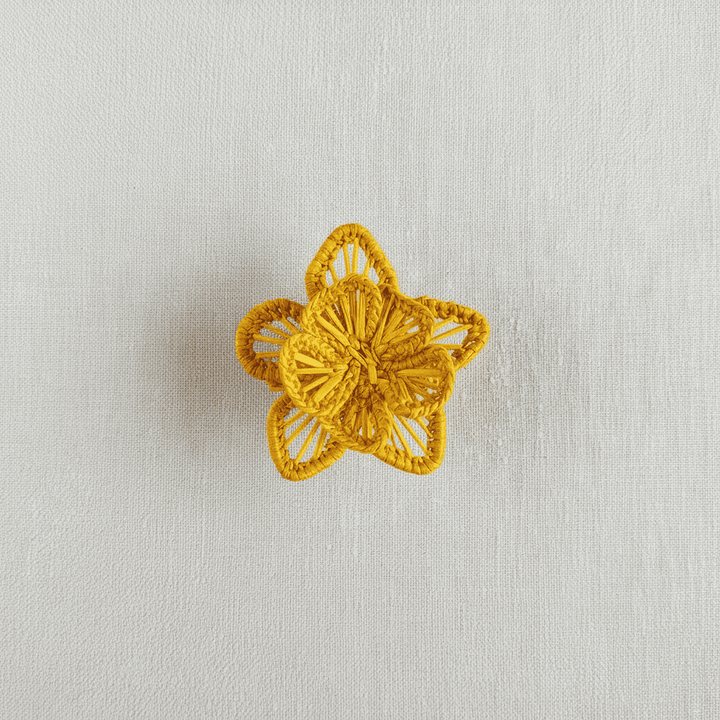 Handwoven star-flower napkin ring in light tan and peach thread accents