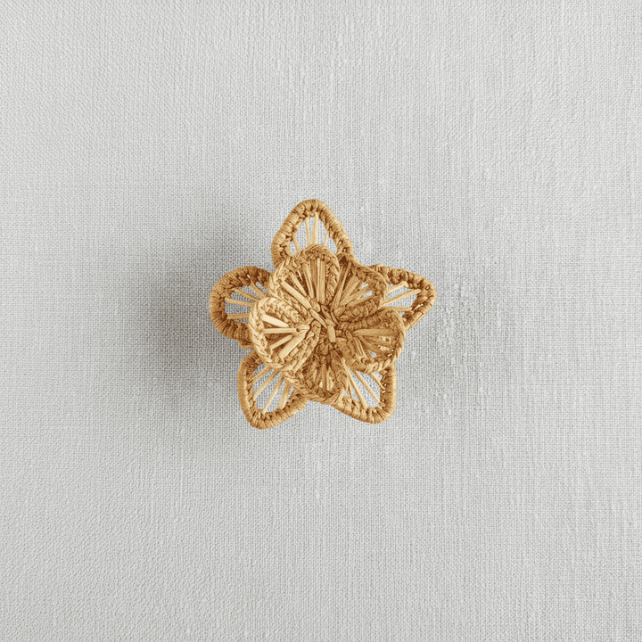 Handwoven star-flower napkin ring in deep green woven palm fibers