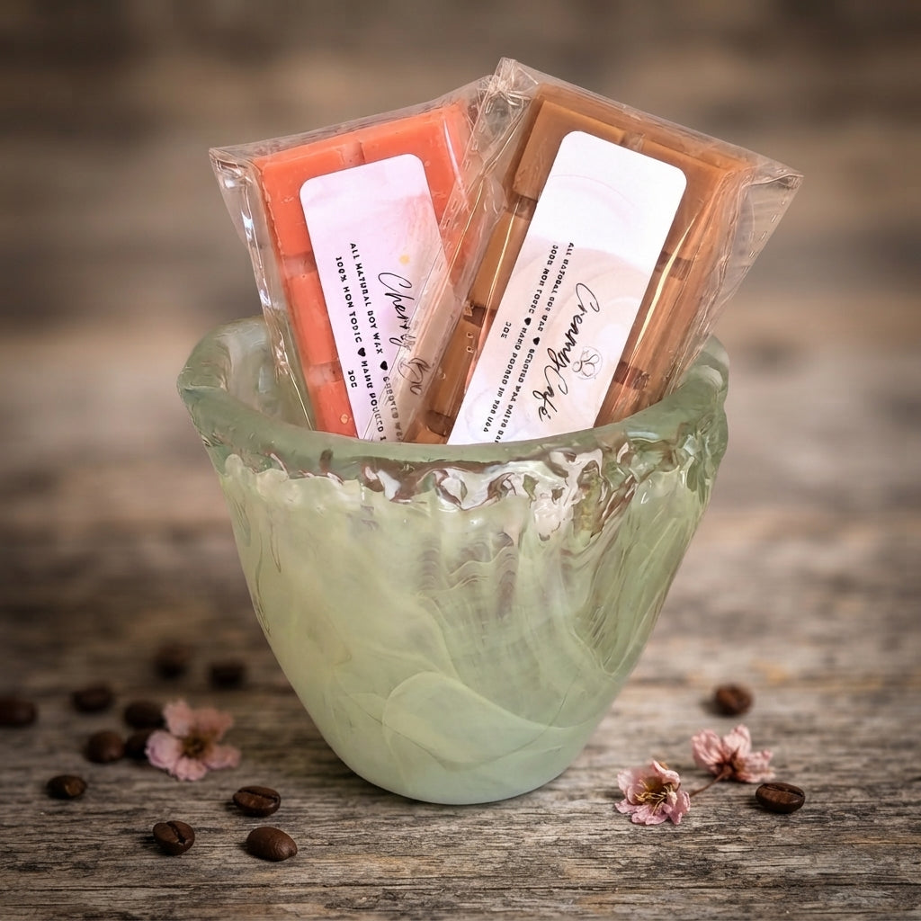 Green decorative cup holding wrapped wax melt bars in orange and cream shades