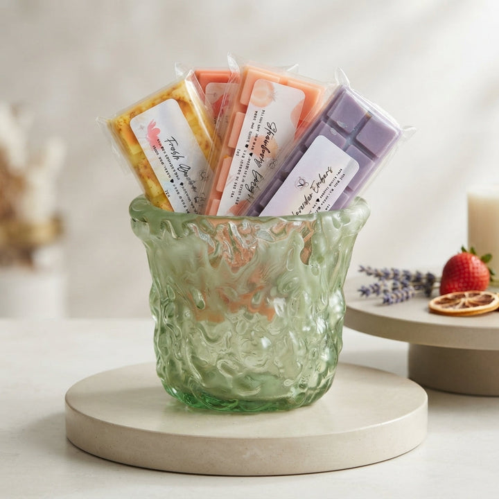 Assorted wax melt bars in wrapped scents, served in a textured green bowl