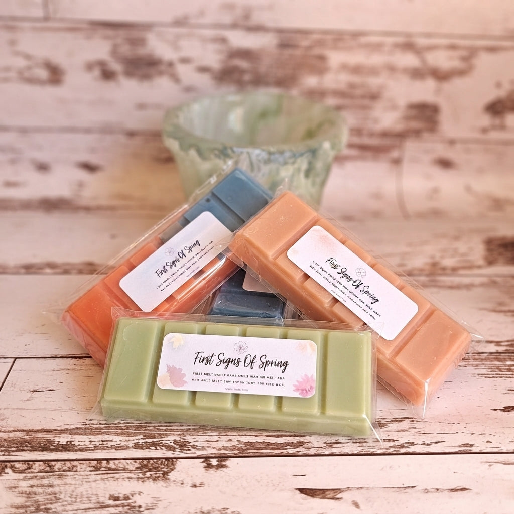 Assorted wrapped wax melt bars in orange, green, and blue, shown in a clear tray