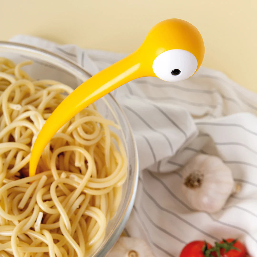 Close-up of yellow monster pasta server eye on a bowl of spaghetti