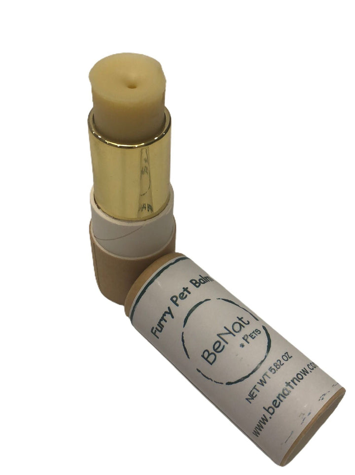 Pet balm stick in gold tube with beige cap, angled close view