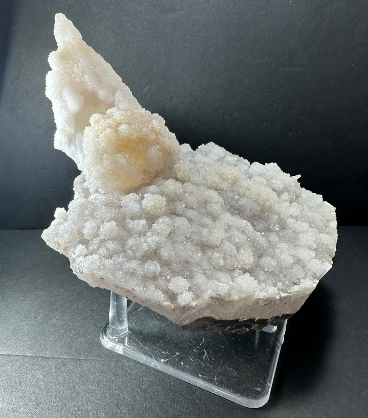 Off-white calcite druse cluster on agate base with tall crystal point