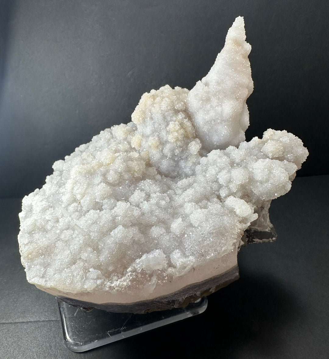 Cream-white calcite druse cluster on dark agate base, sculpted crystal tip