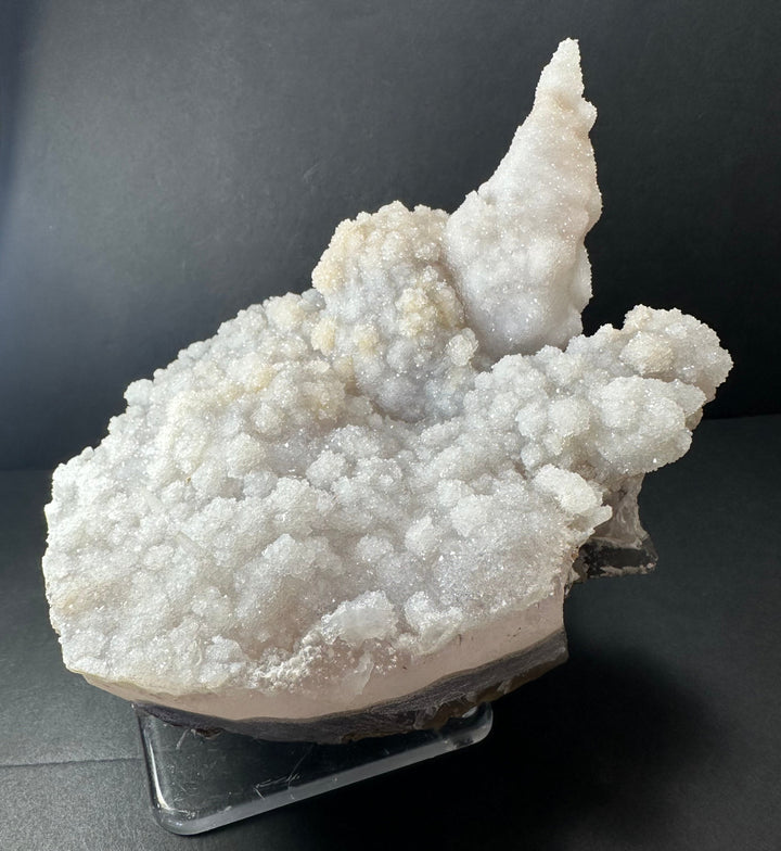 Cream-white calcite druse cluster on dark agate base, sculpted crystal tip