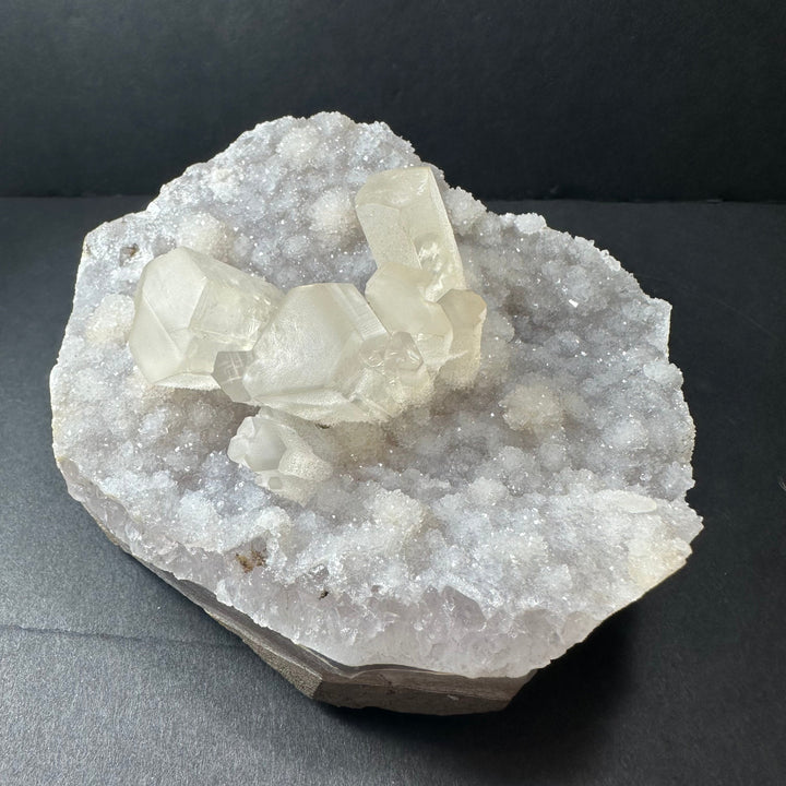 Calcite druse cluster on rough agate base, multiple pale white crystal points