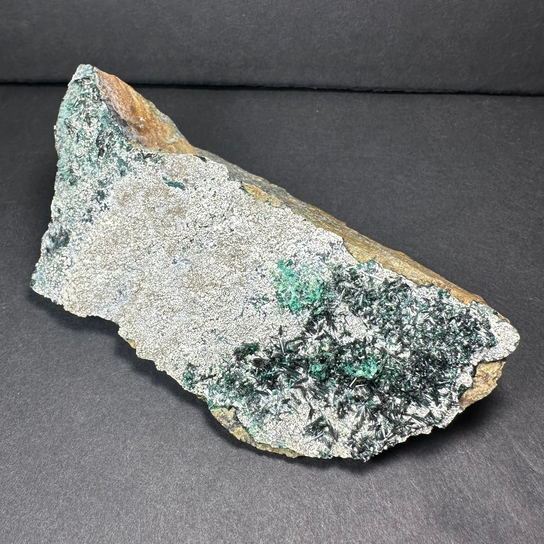 Epidote crystal cluster on dark matrix, green needle-like crystals on gray stone base