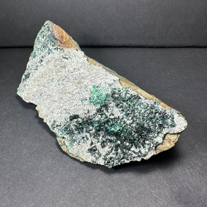 Epidote crystal cluster on matrix, jagged gray base with dense green needle crystals