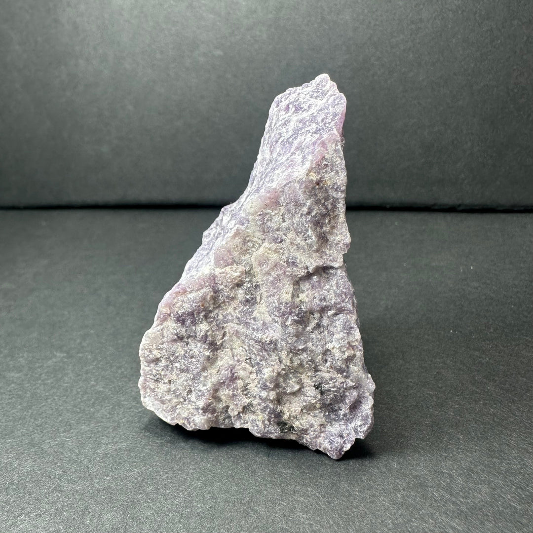 Rough purple lepidolite stone with jagged edges and speckled texture