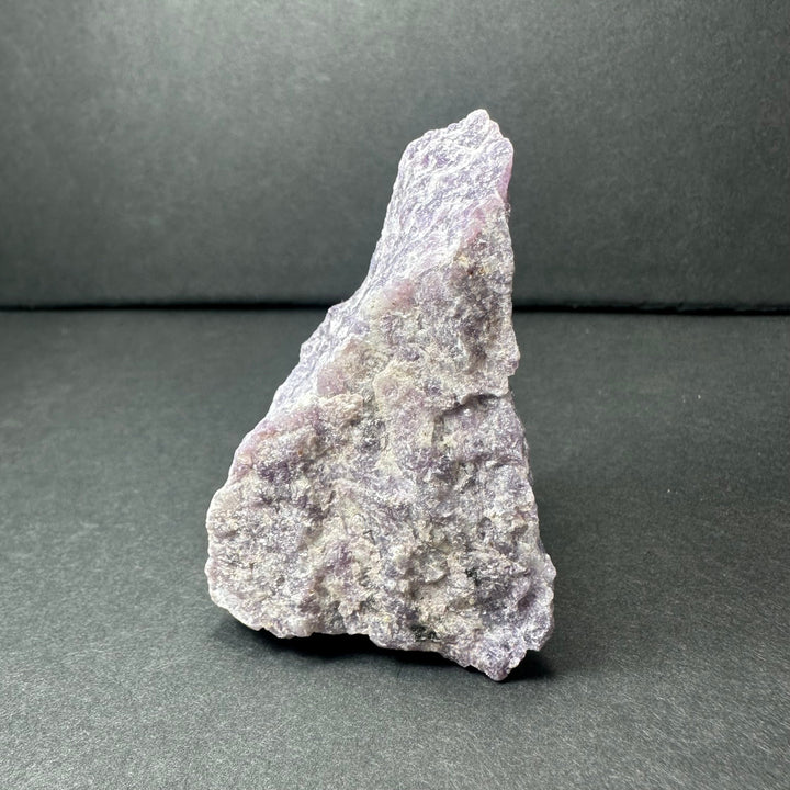 Rough purple lepidolite stone with jagged edges and speckled texture