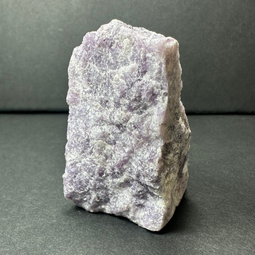 Rough purple lepidolite stone, flat face with crystalline sparkle