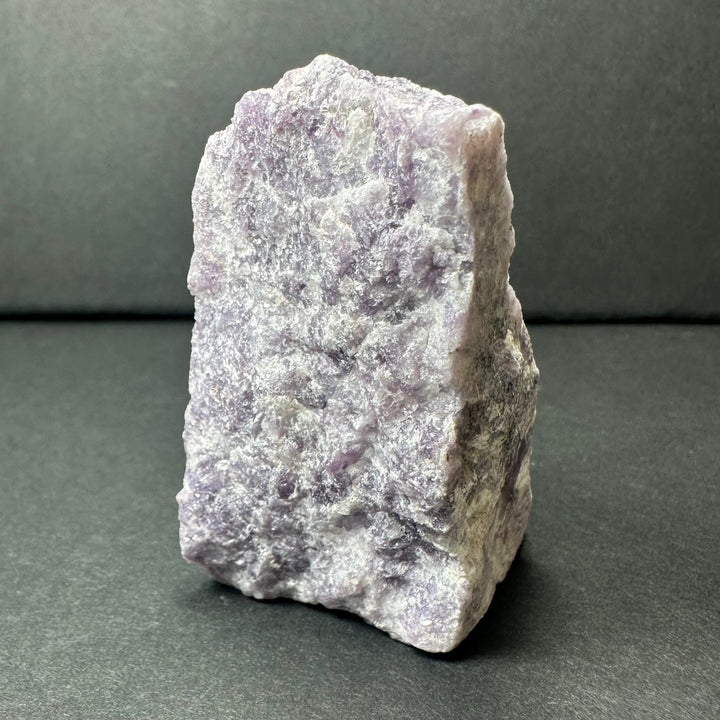 Rough purple lepidolite stone, flat face with crystalline sparkle