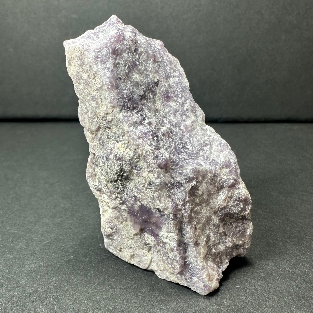 Rough purple lepidolite stone, angled view with violet patches