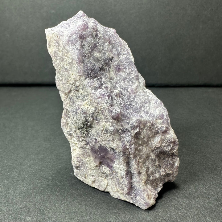 Rough purple lepidolite stone, angled view with violet patches