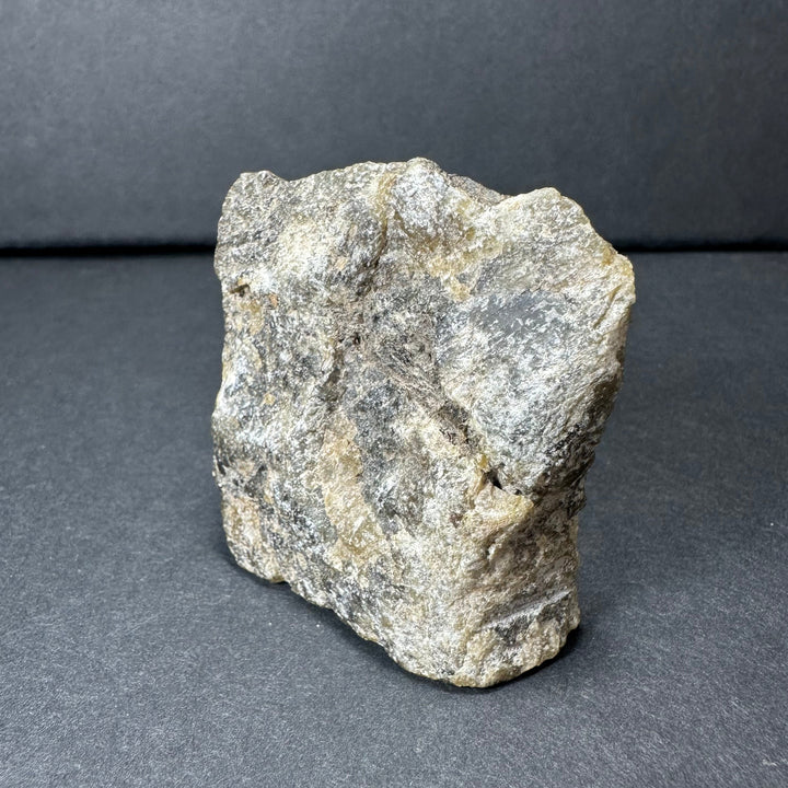 Labradorite rough stone, light gray with yellow-gold flecks and dark specks