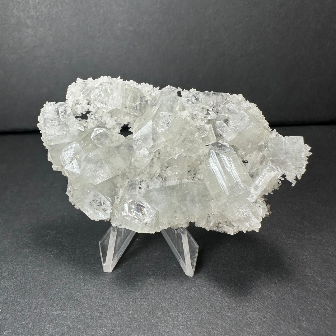 Clear apophyllite crystal cluster micro specimen with sharp white crystal facets on stand