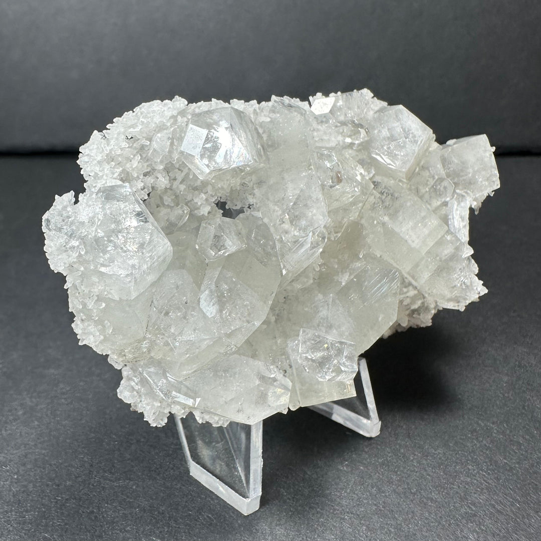 Clear apophyllite crystal cluster micro specimen featuring dense white crystal faces on stand