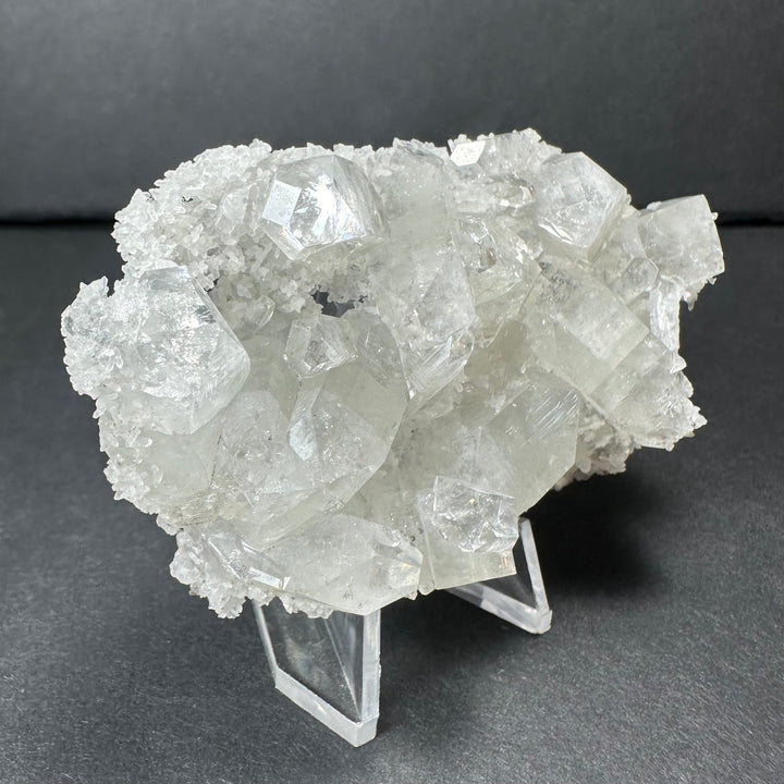 Clear apophyllite crystal cluster micro specimen featuring dense white crystal faces on stand