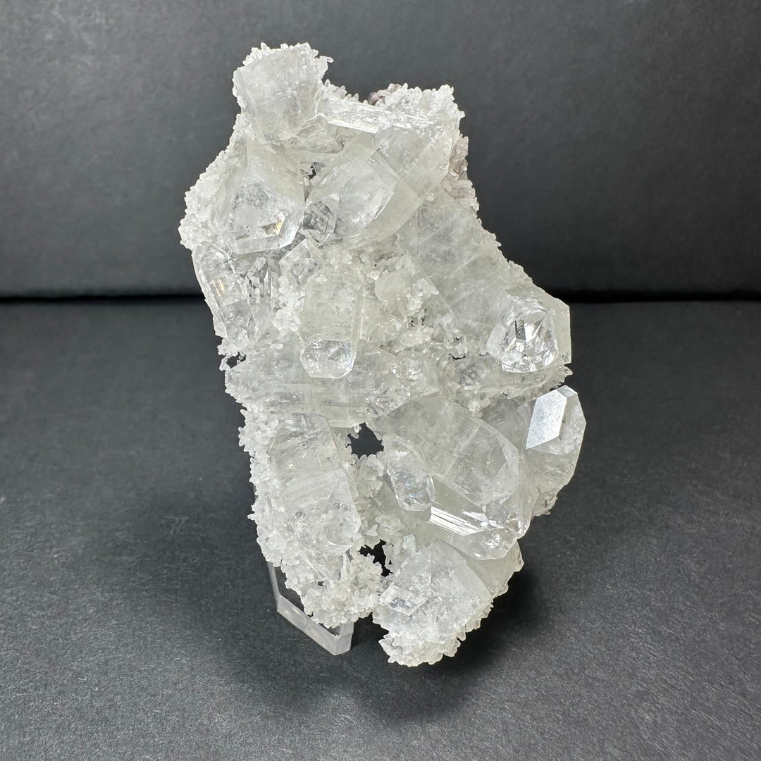 Clear apophyllite crystal cluster micro specimen with rugged white crystal formations on stand